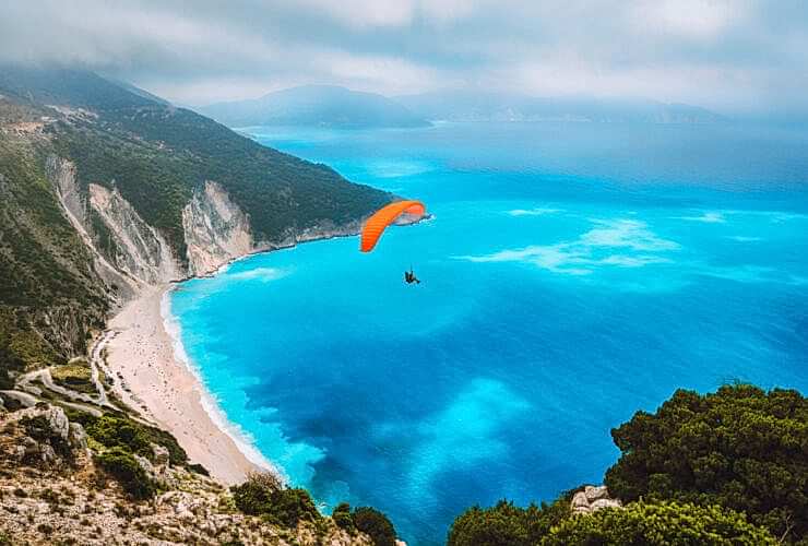 Aerial view of the paraglider flying over gorgeous Myrtos beach. Amazing water colors and beautiful coastline on kefalonia island, Greece